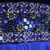Close-up of metallic flower embroidery, sequins, and Swarovski crystals on blue velvet