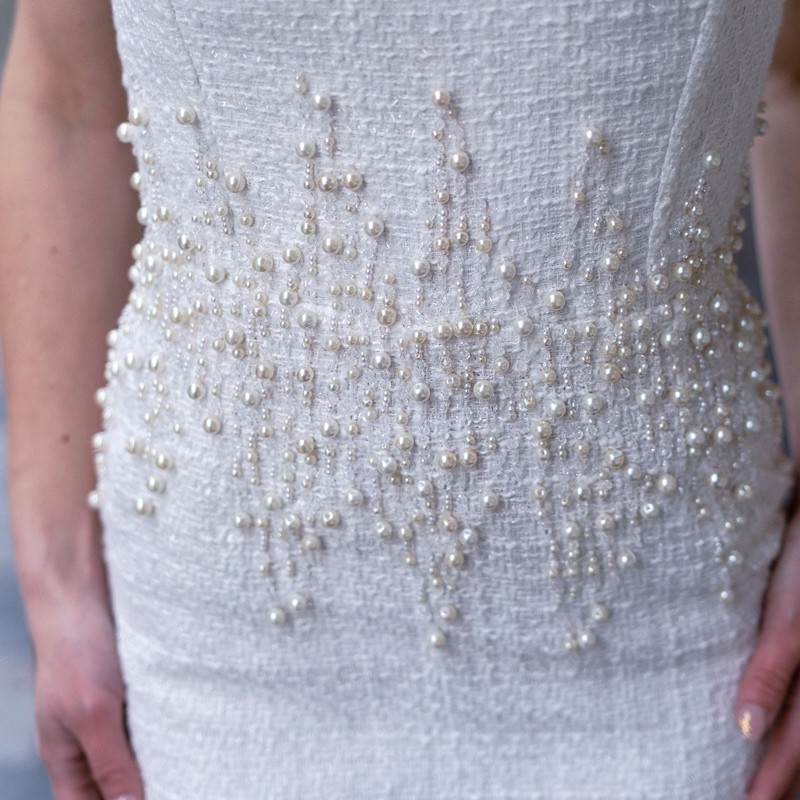 Close-up of pearl embellishments and luxurious tweed fabric on bespoke strapless wedding dress.