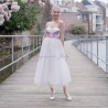 Model wearing strapless floral midi wedding dress with tulle skirt, standing outdoors in natural light