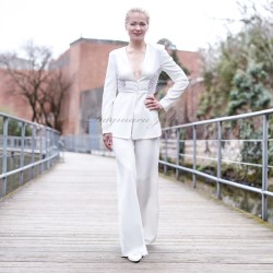 Élégant tailleur pantalon blanc avec blazer à basque longue, orné de broderies artisanales.