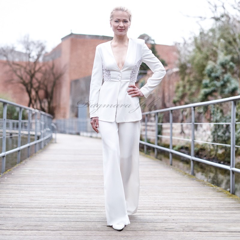 Élégant tailleur pantalon blanc avec blazer à basque longue, orné de broderies artisanales.