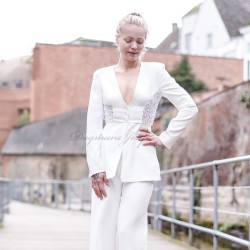 Mannequin portant un costume couture blanc avec pantalon et blazer long à basque, décoré de détails brodés à la main.