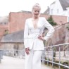 Mannequin portant un costume couture blanc avec pantalon et blazer long à basque, décoré de détails brodés à la main.