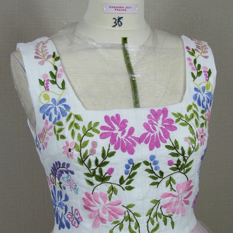 Close-up of artisan embroidery   on linen bodice of midi tulle dress
