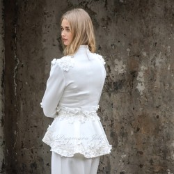 Gros plan sur les détails couture : appliqués floraux, boutons nacrés et dentelle délicate sur un tailleur de mariée.