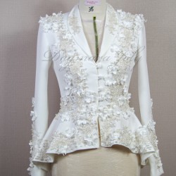 Gros plan sur les détails couture : appliqués floraux, boutons nacrés et dentelle délicate sur un tailleur de mariée.