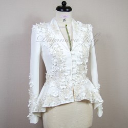 Gros plan sur les détails couture : appliqués floraux, boutons nacrés et dentelle délicate sur un tailleur de mariée.