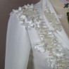 Gros plan sur les détails couture : appliqués floraux, boutons nacrés et dentelle délicate sur un tailleur de mariée.