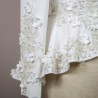 Gros plan sur les détails couture : appliqués floraux, boutons nacrés et dentelle délicate sur un tailleur de mariée.