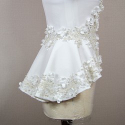 Gros plan sur les détails couture : appliqués floraux, boutons nacrés et dentelle délicate sur un tailleur de mariée.
