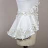 Gros plan sur les détails couture : appliqués floraux, boutons nacrés et dentelle délicate sur un tailleur de mariée.