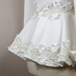 Gros plan sur les détails couture : appliqués floraux, boutons nacrés et dentelle délicate sur un tailleur de mariée.