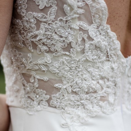 Détail du dos nu en V avec dentelle et perles sur robe de mariée