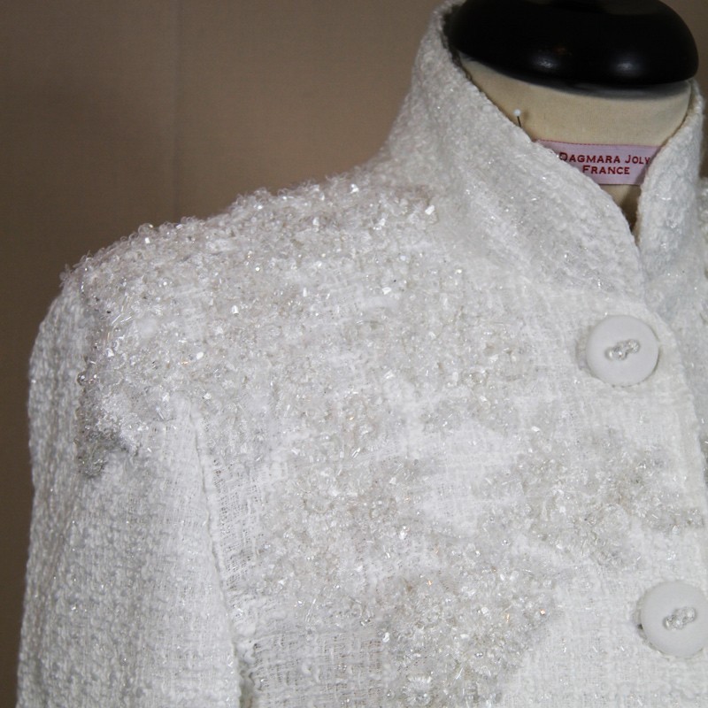 Close-up of shiny embellishments on luxury white tweed fabric