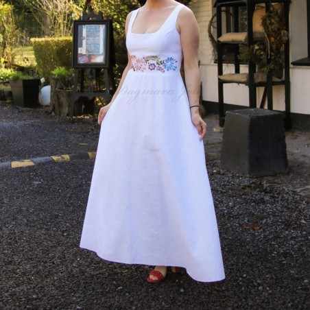 Model wearing floor-length embroidered linen wedding dress in outdoor countryside setting – elegant and rustic bridal look
