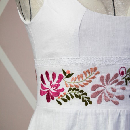 Detailed close-up of embroidered hem on linen wedding dress – hand-stitched floral pattern on soft natural fabric
