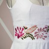 Detailed close-up of embroidered hem on linen wedding dress – hand-stitched floral pattern on soft natural fabric