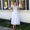 Robe de mariée midi en lin portée par une mariée dans un jardin, avec un décolleté cœur et une jupe fluide