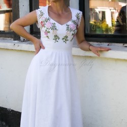 Gros plan sur le décolleté cœur romantique d’une robe de mariée en lin brodé, sur fond naturel.