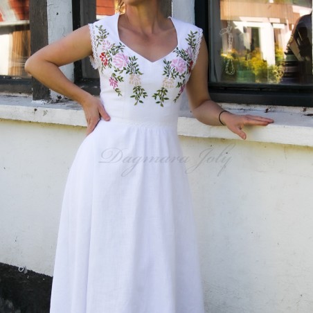 A bride wearing a midi-length linen wedding dress with a heart neckline and embroidery, standing gracefully in natural light