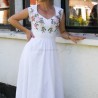 Gros plan sur le décolleté cœur romantique d’une robe de mariée en lin brodé, sur fond naturel.