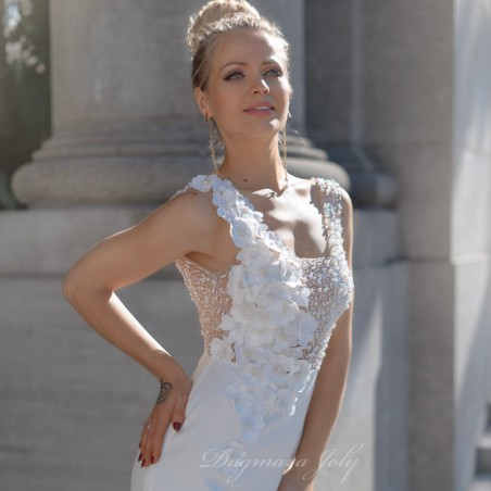 Vue trois-quarts de la robe de mariée, mettant en valeur les fleurs, les perles et la coupe tube élégante
