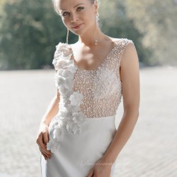 Half-front close-up of bridal gown with pearl and flower details on bodice, flowing seamlessly into a fitted tube silhouette