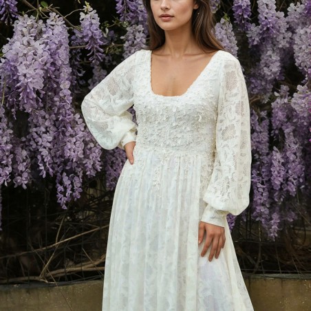Vue de face d'une robe de mariée midi en dentelle transparente, avec manches ballon et ornements délicats