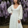 Vue de face d'une robe de mariée midi en dentelle transparente, avec manches ballon et ornements délicats