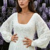 Vue de face d'une robe de mariée midi en dentelle transparente, avec manches ballon et ornements délicats