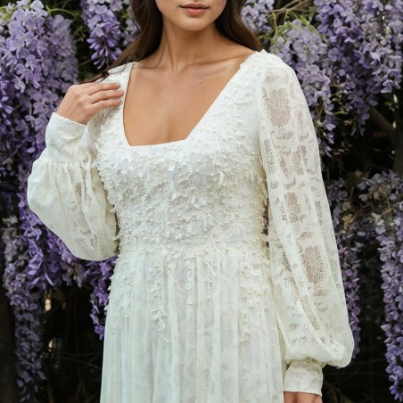 Vue de face d'une robe de mariée midi en dentelle transparente, avec manches ballon et ornements délicats