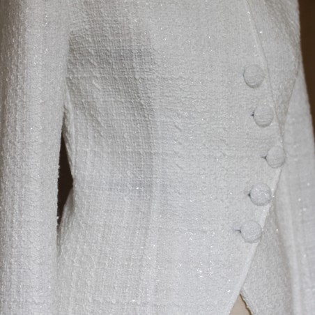 Close-up of women's white bridal asymmetrical tweed jacket fabric showing textured tweed and stitching.