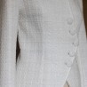 Zoom sur le tissu de la veste de mariée blanche asymétrique en tweed montrant le tweed texturé et les coutures