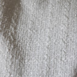 Zoom sur le tissu de la veste de mariée blanche asymétrique en tweed, montrant le tweed texturé et les coutures