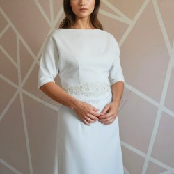Gros plan sur le corsage de la robe de mariée longue fourreau, montrant les détails brodés et la texture légère des manches