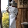 Bride standing in off-shoulder sheath wedding gown with train flowing behind"
