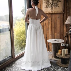 Vue de dos d’une robe de mariée faite main, avec dos nu à col licou, détails en dentelle et tissu en coton floral.