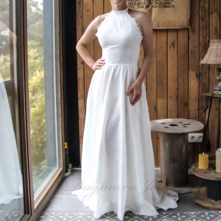 Woman standing in an elegant French-made wedding dress with asymmetrical hem and train.