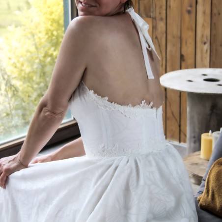 Back view of a handmade wedding gown with open halter back, lace detailing, and floral cotton fabric.