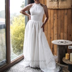 Model in a floor-length cotton halter neck wedding dress with a flowing train, posing