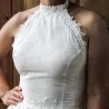Gros plan sur les détails en dentelle délicate du corsage d’une robe de mariée en coton à col licou.