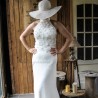 Front view of hand-cut flower appliqués, pearls, and transparent shiny tubes on the bodice of a lace wedding dress.
