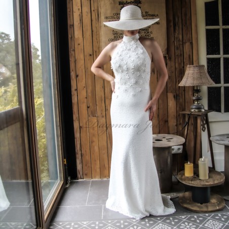 Front profile of a bride in a floor-length sheath lace dress featuring pearl and transparent tube decorations.