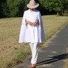 Bride walking in a minimalist white bridal cape with silver buttons, captured in natural light