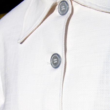 Close-up of silver button detailing on the front of a white cotton bridal cape with a tailored neckline.