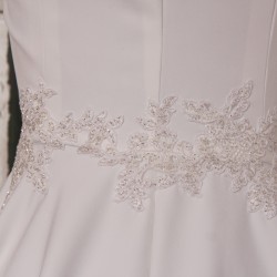 Gros plan sur les finitions brodées à la main de la robe de mariée