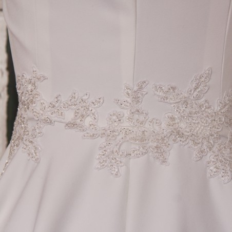 Gros plan sur les finitions brodées à la main de la robe de mariée