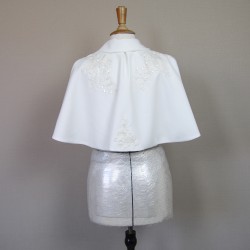 Gros plan sur cape de robe de mariée faite main ornée de dentelle, sequins et cristaux.