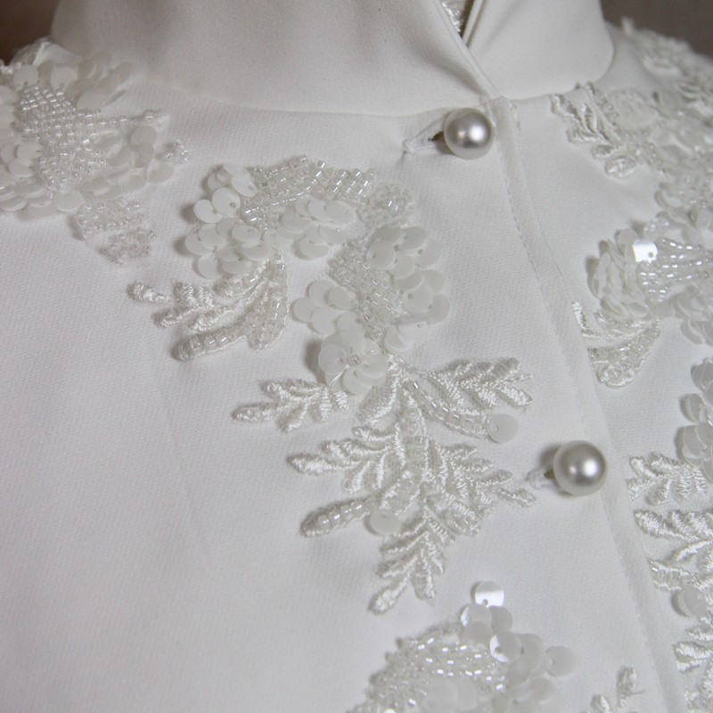 Close-up of delicate hand-embroidered beadwork on short crepe bridal cape.