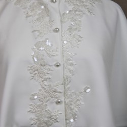Gros plan des détails ornés à la main d’une petite cape de mariage.